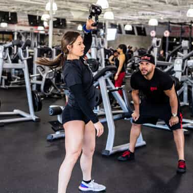 A woman performs kettlebell lifts with a trainer