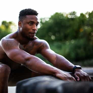 A man squats with a tire